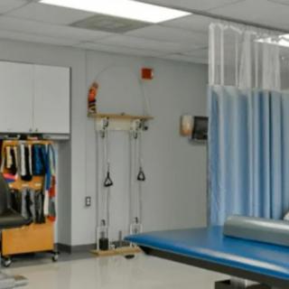 A physical therapy treatment room with exercise equipment and a padded table.
