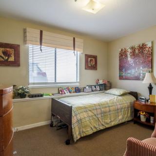 A cozy bedroom with a single bed, decorated walls, and natural light coming through the window.