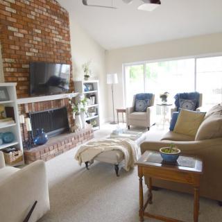 A cozy living room featuring a brick fireplace, comfortable seating, and a TV.