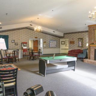 A spacious game room with a table tennis setup, seating area, and a cozy fireplace.