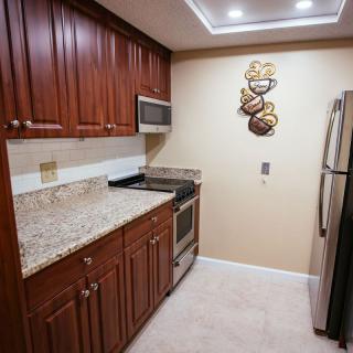A modern kitchen with wooden cabinets, granite countertops, and stainless steel appliances.