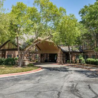 The entrance of a building surrounded by trees and a driveway.
