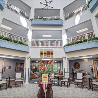 A spacious atrium with multiple balconies, featuring a modern seating area and decorative plants.