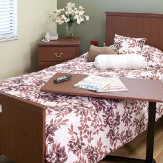 A cozy bedroom featuring a neatly made bed with floral bedding and a side table.