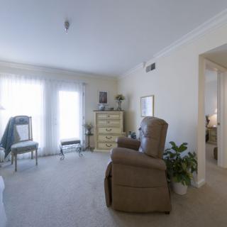 A bright and minimalist living room with an armchair and dresser.