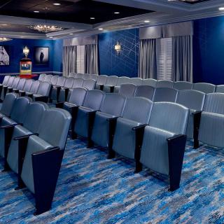 A modern, blue-themed empty theater with tiered seating.