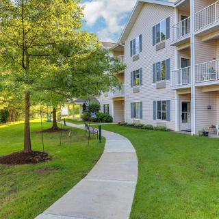 A modern apartment building with balconies, surrounded by lush greenery and a winding pathway.