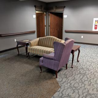A cozy seating area featuring a striped couch and a purple chair, set in a well-lit indoor space.