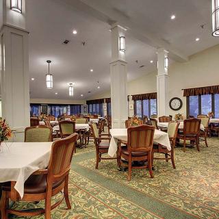 A spacious and elegantly designed dining area with multiple tables and chairs, well-lit with overhead lights.