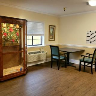 A cozy interior of a room featuring a table, chairs, and a display case with decorative items.