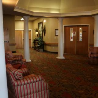 A well-lit lobby with striped armchairs, columns, and a patterned carpet.