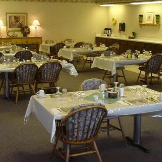 An empty dining room with tables set for a meal.