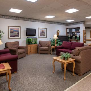 A cozy lounge area featuring comfortable seating, a television, and indoor plants.