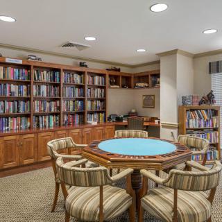A cozy library room with a round table and chairs surrounded by bookshelves.