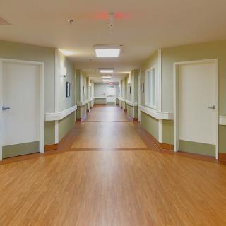 An empty hospital corridor with multiple doors on both sides.