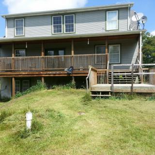 A two-story house with a wooden deck and a grassy lawn.