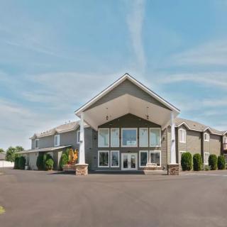 A modern hotel building with a spacious driveway under a clear sky.