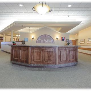 A well-lit hotel reception area featuring a large wooden desk.
