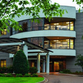 A modern office building with a sleek design, surrounded by lush greenery.