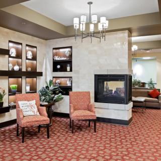 A cozy living room with armchairs, a fireplace, and decorative shelves.
