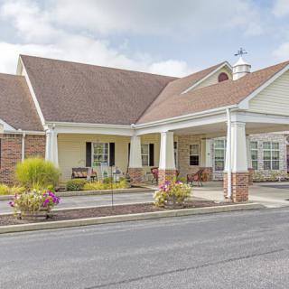 A well-maintained building entrance with landscaped surroundings and a paved driveway.