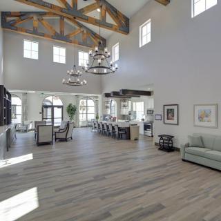 A spacious and modern living room with high ceilings, featuring elegant chandeliers and wooden beams.