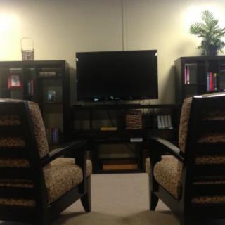 A cozy living room setup featuring two chairs facing a television, flanked by bookshelves with decor.