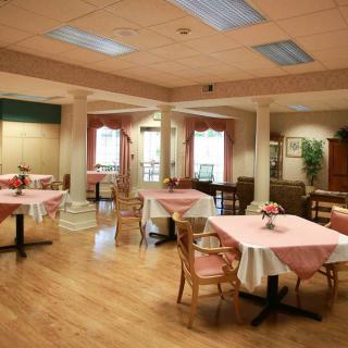 A cozy dining area with neatly arranged tables and chairs in a warmly lit environment.