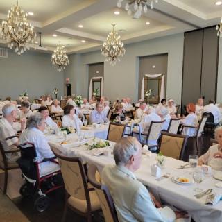 A formal banquet event with guests seated at long tables in an elegantly decorated room.
