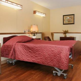 A neatly made hospital bed in a well-furnished room.