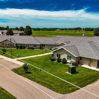 Aerial view of a suburban residential area with well-maintained lawns and roads under a clear sky.