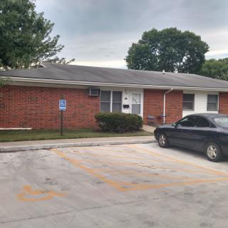 A brick residential building with a car parked in the parking lot.