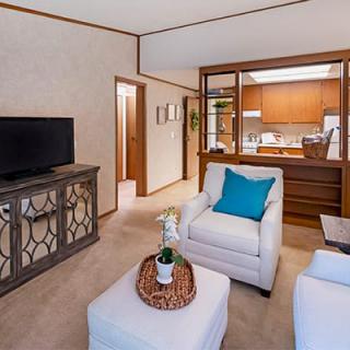 A cozy living room with a view into the kitchen, featuring comfortable seating and modern decor.