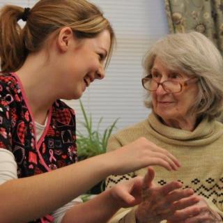 A caregiver engages in a friendly conversation with an elderly woman.