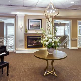 A sophisticated lobby featuring a grand piano, floral centerpiece, and a cozy fireplace.
