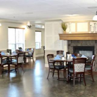 A cozy dining area with tables and chairs arranged around a central fireplace.