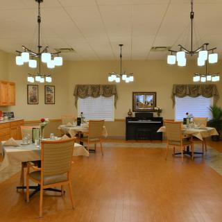 A spacious and well-lit dining room with neatly arranged tables and chairs, featuring elegant lighting fixtures and decorative elements.