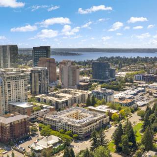 A vibrant aerial view of an urban cityscape featuring tall buildings and a nearby lake under a clear blue sky.