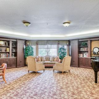 A spacious library with comfortable seating, bookshelves, and a piano.