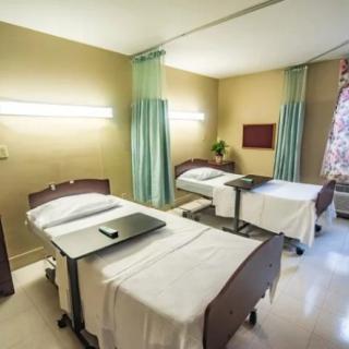 A hospital room with two beds separated by curtains.