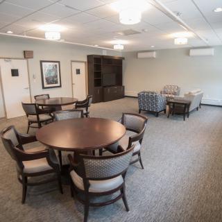 A spacious conference room with a large table and multiple chairs arranged on a carpeted floor.