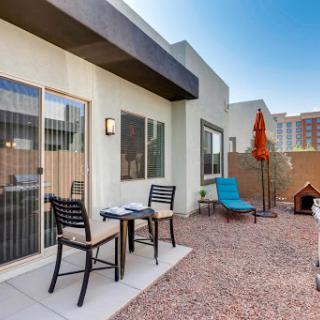A cozy outdoor patio space featuring chairs, a small table, and a sunshade for relaxation.