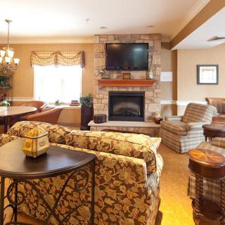 A cozy living room featuring a stone fireplace and a mounted television, with comfortable sofas and warm decor.