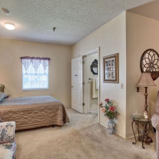 A cozy bedroom with a neatly made bed, a standing lamp, and decorative elements.