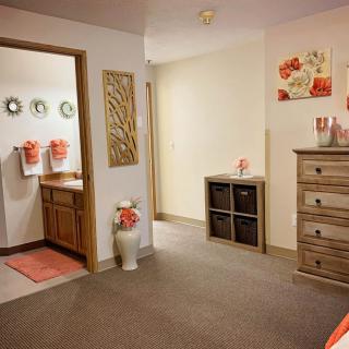 Cozy interior view of a bedroom leading to a bathroom, featuring warm decor and wooden furniture.