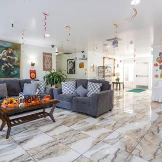 A well-decorated living room featuring gray sofas, a wooden coffee table with decorative items, marble flooring, and vibrant artwork.
