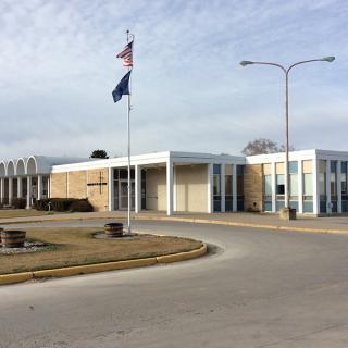 A school building with flags flying in front on a cloudy day.