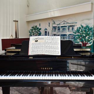 A grand piano with sheet music placed on it in a decorated room.