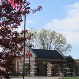 A small brick building surrounded by trees under a blue sky.