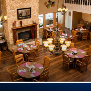 A cozy dining area featuring wooden tables and chairs, set around a fireplace.